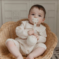 Load image into Gallery viewer, Baby sitting in a wicker chair holding a pacifier case and pacifier, with a neutral background.